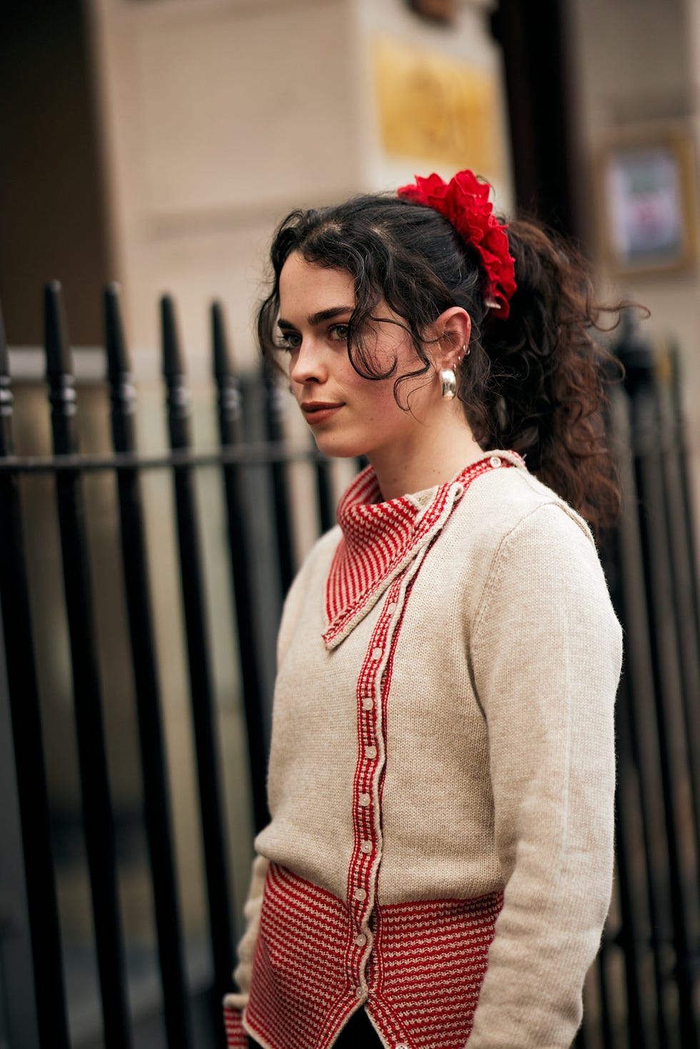 a person dressed in a unique sweater with red detailing and a hair accessory best fringe haircuts london fashion week street style