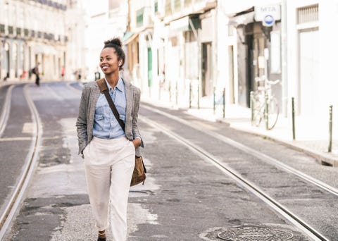 Smiling young woman with wireless earphones in the city on the go, Lissabon, Portugal Smiling young woman with wireless earphones in the city on the go, Lissabon, Portugal
