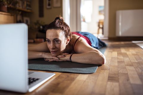 Young woman using a laptop while doing yoga