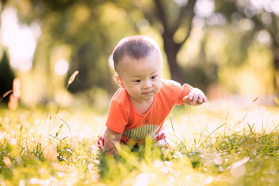 1 year old baby boy crawling around in short grass, used in a story about long names for boys