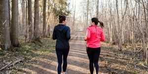 long shot of two sportive women running stitching away from the camera in the forest