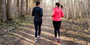 long shot of two sportive women running away from the camera in the forest