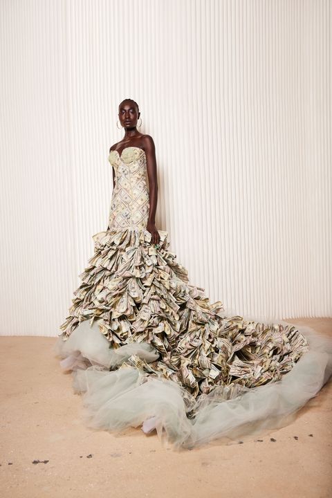 a model wears a dress made of paper money
