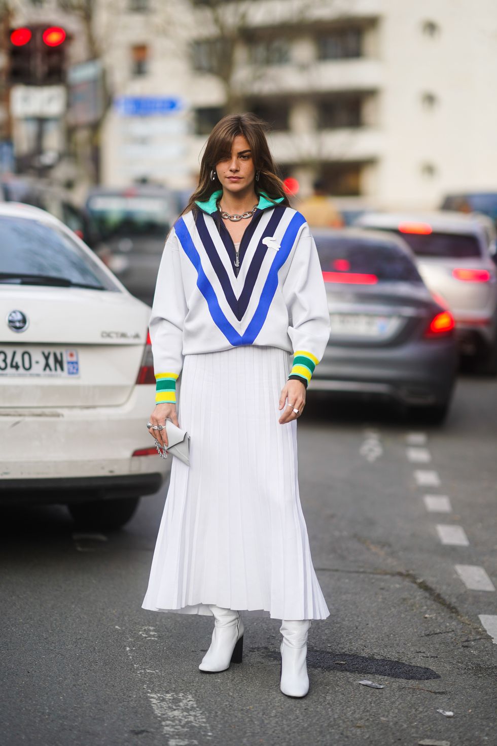 paris, france   march 03 clara berry wears a blue black and white striped v neck lacoste pullover with colored cuffs, a white pleated skirt, a clutch, white boots, outside lacoste, during paris fashion week   womenswear fallwinter 20202021 on march 03, 2020 in paris, france photo by edward berthelotgetty images
