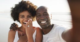 cropped portrait of an affectionate young couple taking selfies on the beach after their engagement