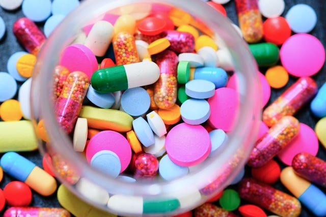 Looking down on a open prescription bottles with assorted pills
