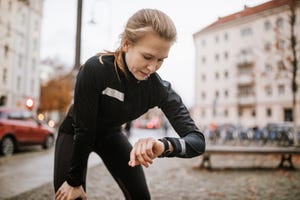 young fitness woman looking at her smart watch while taking a break during workout female urban runner checking fitness app on her smartwatch while taking a breather