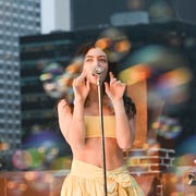 Lorde lorde wears a yellow crop top and sings into a microphone, surrounded by bubbles