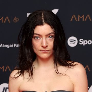 a woman stares at the camera, she wears a gray strapless gray top
