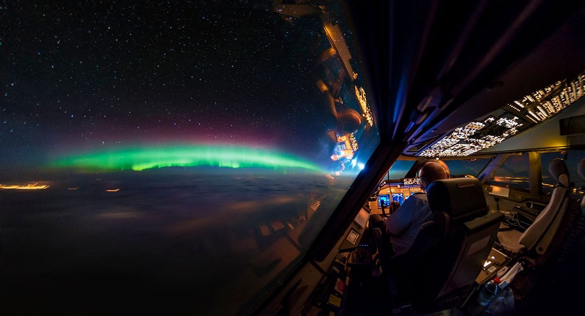 Het noorderlicht boven Canada gefotografeerd over de schouder van een collegapiloot