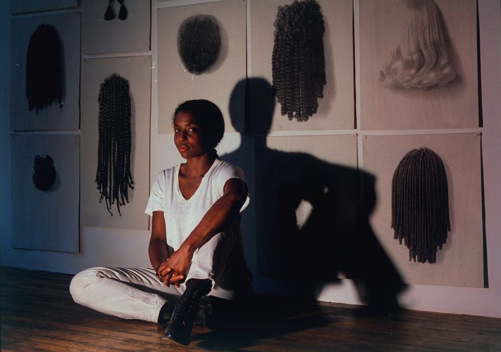 Lorna Simpson sitting on the floor in her studio in front of her installation Wigs