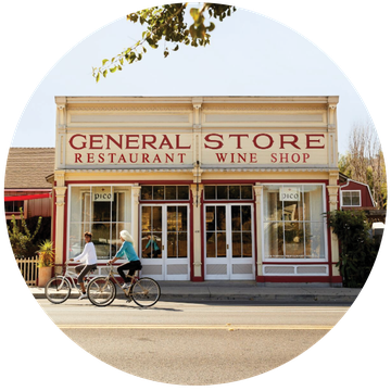 a couple of people riding bikes in front of a store in los alamos, californina