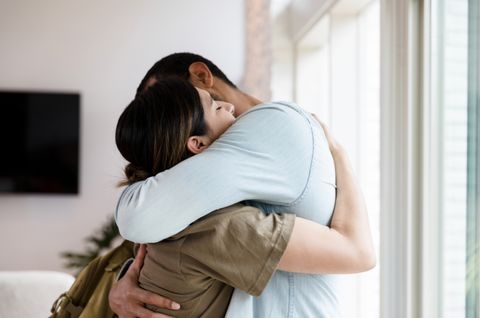sad mid adult  female soldier hugs her husband goodbye as she leaves for military duty