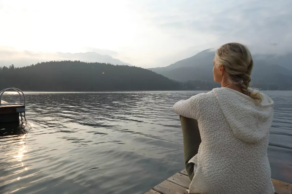 woman sitting on pier looking at lake
