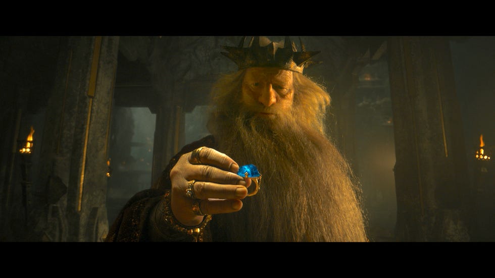 a man with a long beard and a hat holding a small blue object