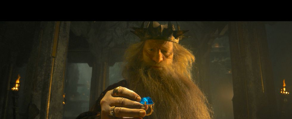 a man with a long beard and a hat holding a small blue object