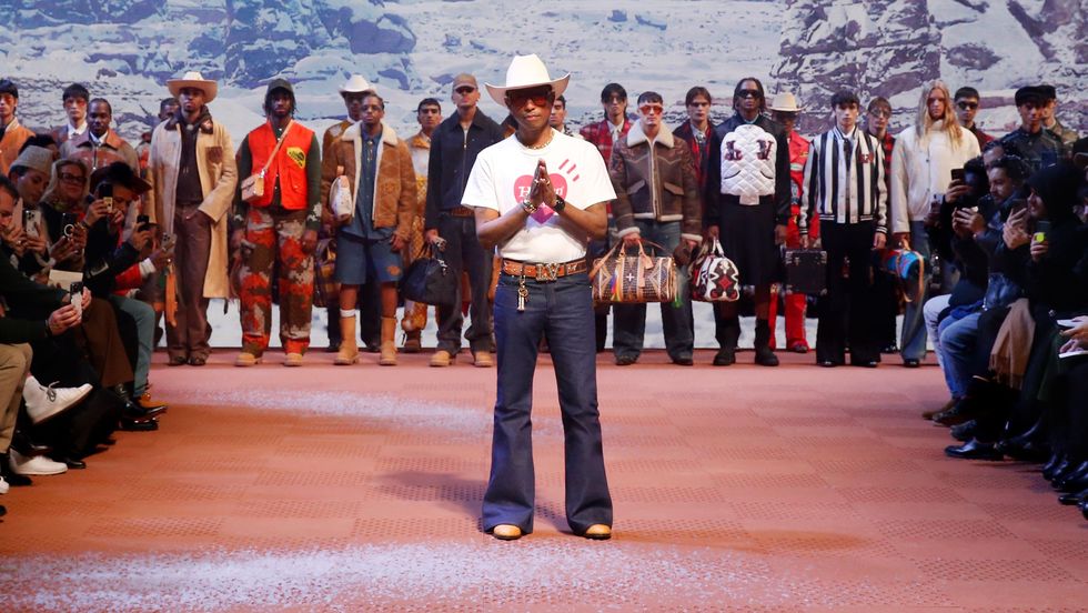 a person in a white shirt and cowboy hat standing in front of a crowd of people