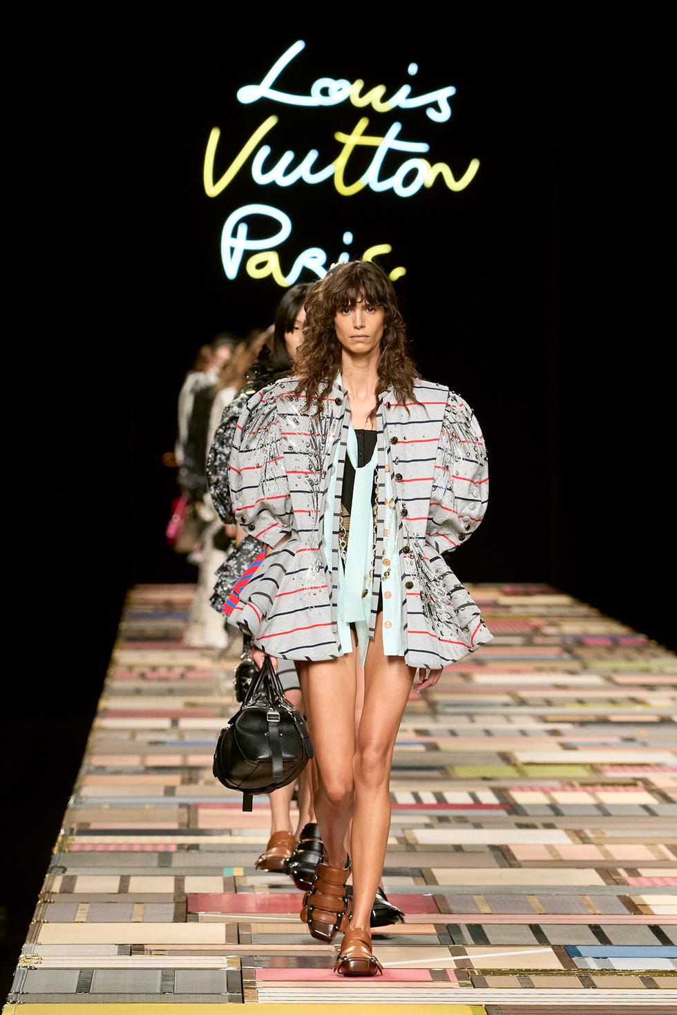 Runway scene showcasing a fashion model in a striped oversized jacket