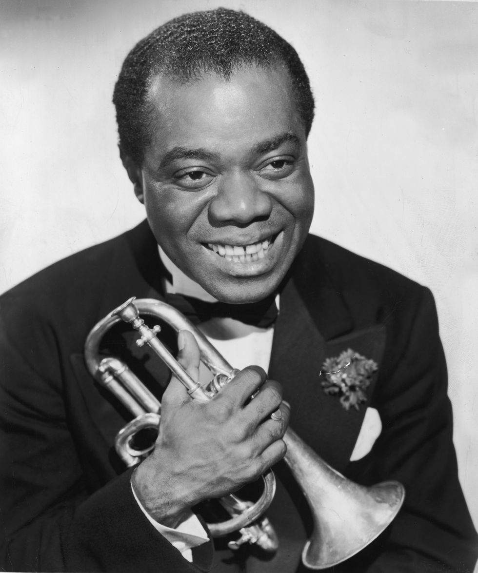 Gap-Toothed Grinners: circa 1945:  Headshot portrait of American jazz musician Louis Armstrong (1901 - 1971) smiling and holding a cornet against his chest. He is wearing a jacket and a bow tie.