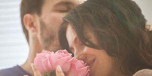 adult man and woman with bouquet of pink roses sharing what looks like a romantic moment