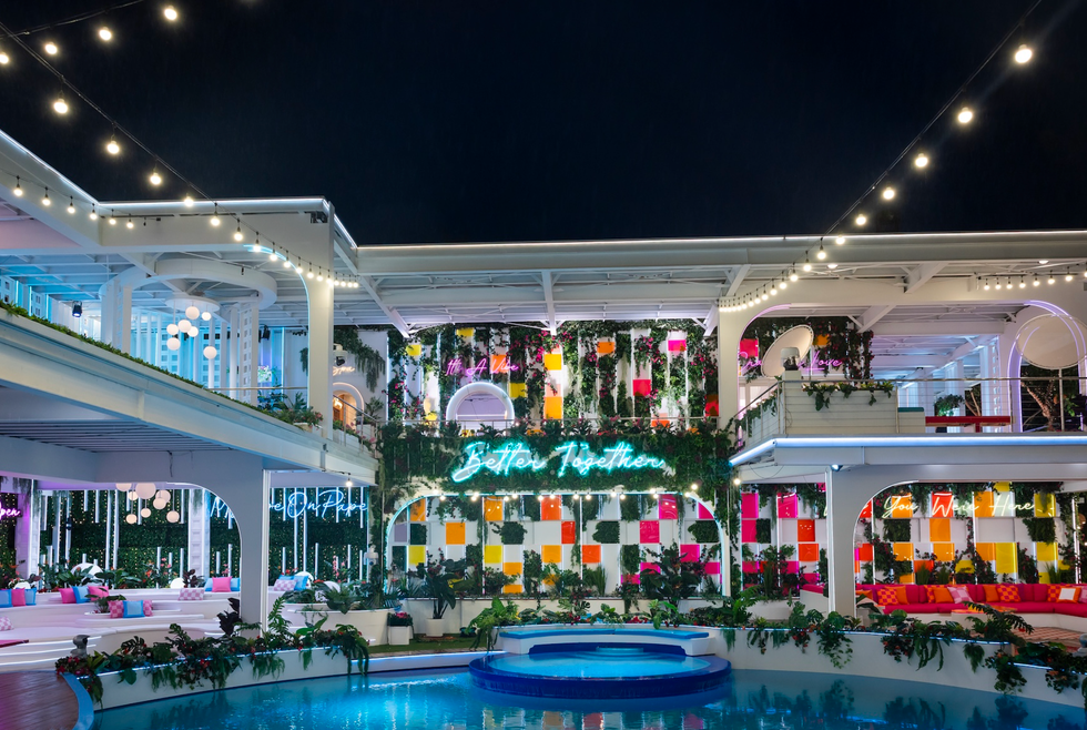 a vibrant and modern recreational space at night with neon signage and lush plants