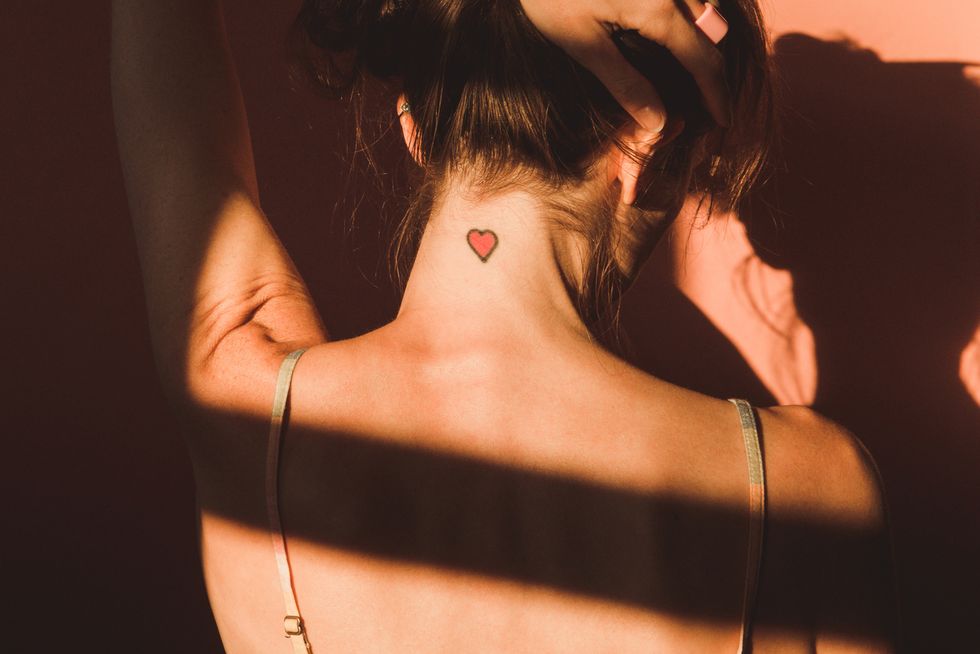 love, relationships and loneliness woman back view with heart tattoo on neck