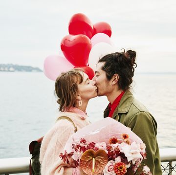 couple holding heart shaped balloons kissing while exploring city