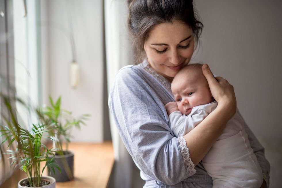loving and affectionate mother holding newborn baby indoors at home
