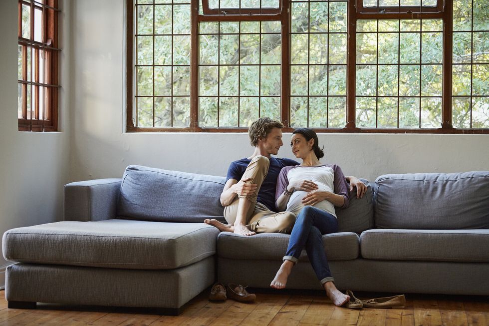 loving expectant couple sitting on sofa at home
