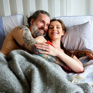 Loving pregnant couple embracing on bed at home