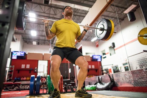 low angle of man completing squats at the gym