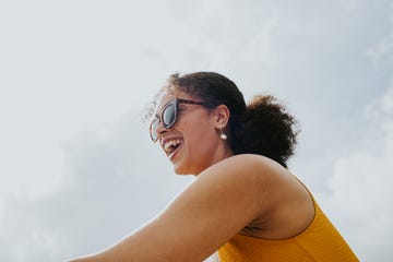 low angle portrait of a young, beautiful mixed race woman wearing sunglasses and a swimsuit