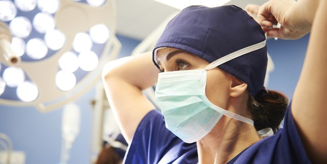 Low Angle View Of Doctor Tying Surgical Mask In Hospital