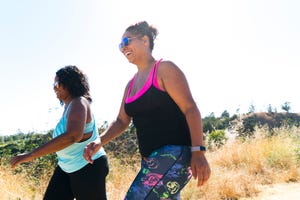 low angle view of happy female friends walking on field against clear sky