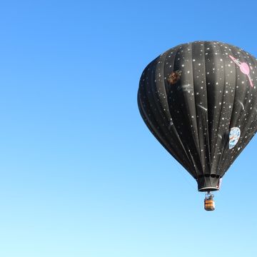 Low Angle View Of Hot Air Balloon Flying In Clear Blue Sk