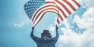 low angle view of man against sky holding american flag