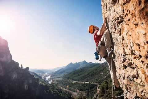 Low Angle View Of Man Rock Climbing Against Sky
