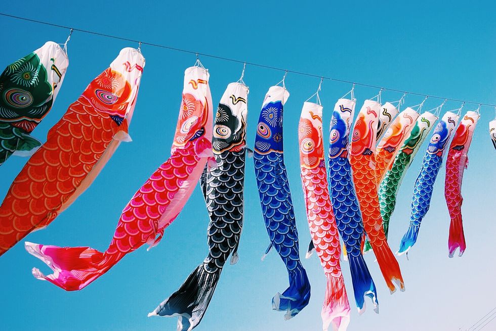 low angle view of multi colored koinobori hanging against clear blue sky