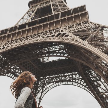Low Angle View Of Woman Standing In Front Of Eiffel Tower