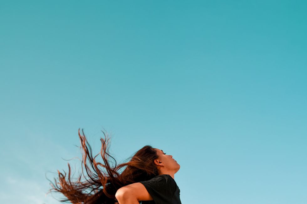 low angle view of woman with long hair standing against clear blue sky