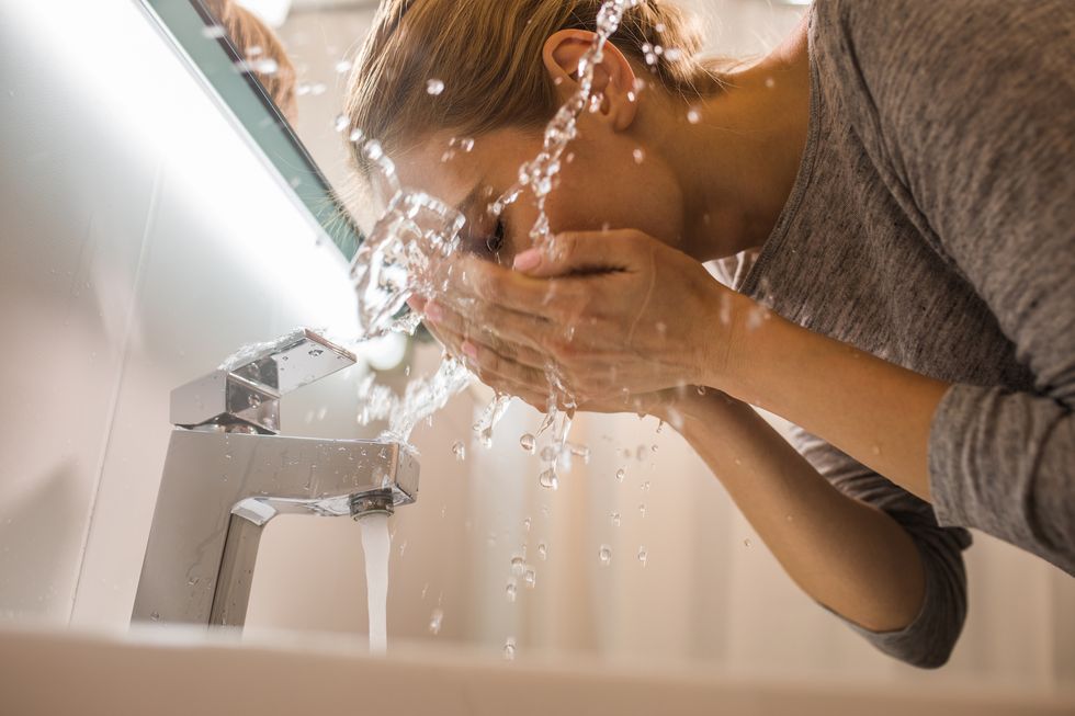 low angle view of young woman washing her face in the bathroom