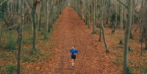 low angled drone view of a runner on a treelined trail