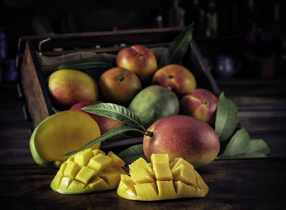 low key image close up of sliced ripe mangoes in rustic kitchen