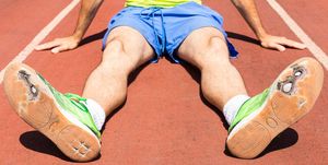 low section of athlete with torn shoes sitting on track