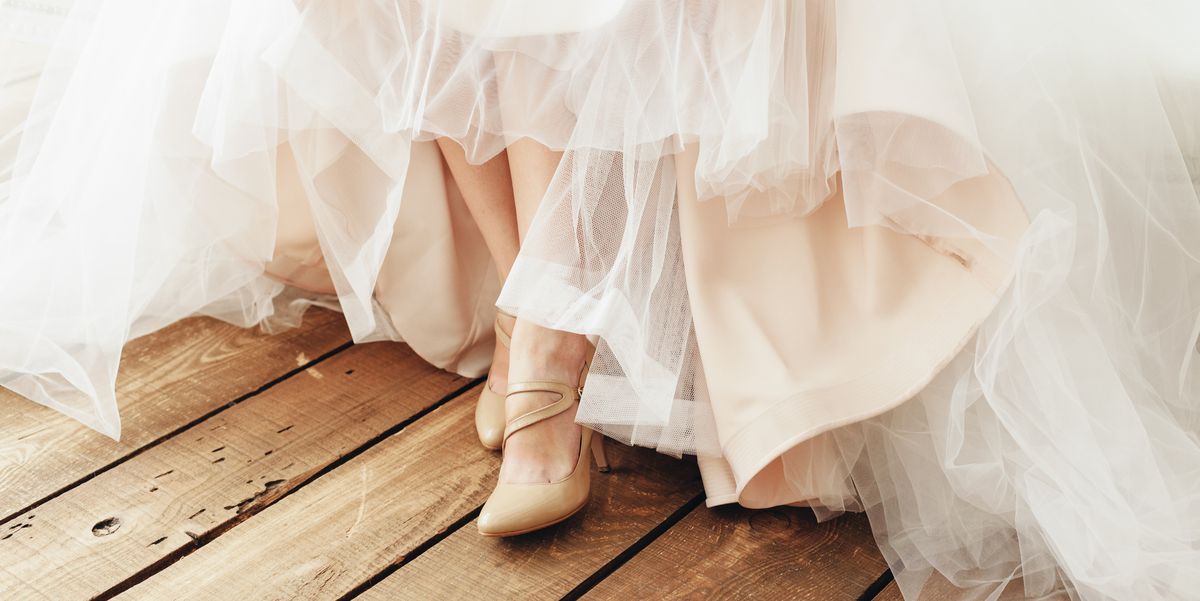 low section of bride wearing wedding dress and shoes while standing on hardwood floor