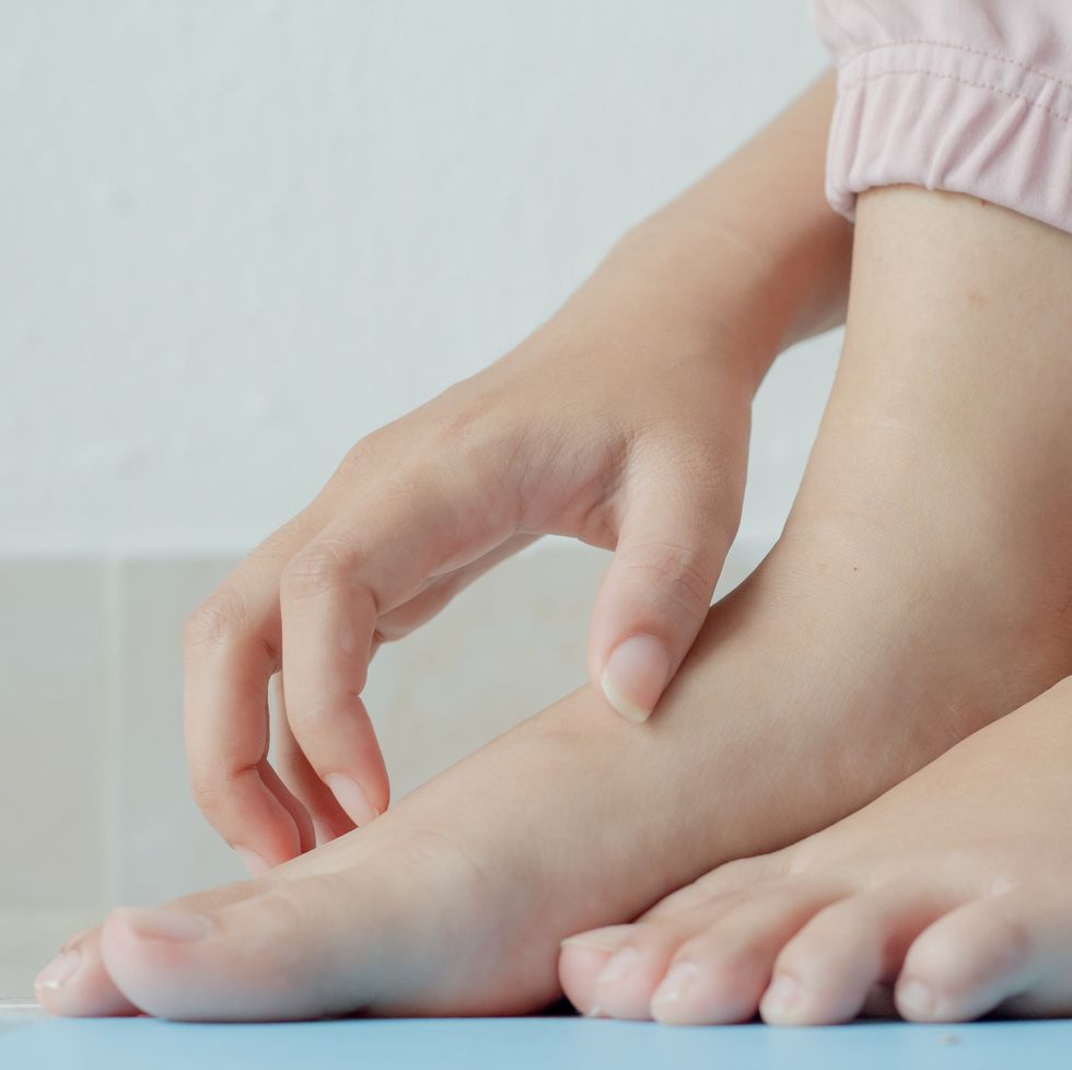 low section of child scratching foot on floor
