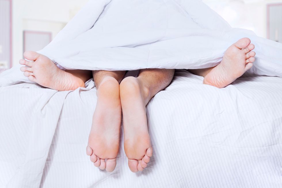 Low Section Of Couple Lying On Bed