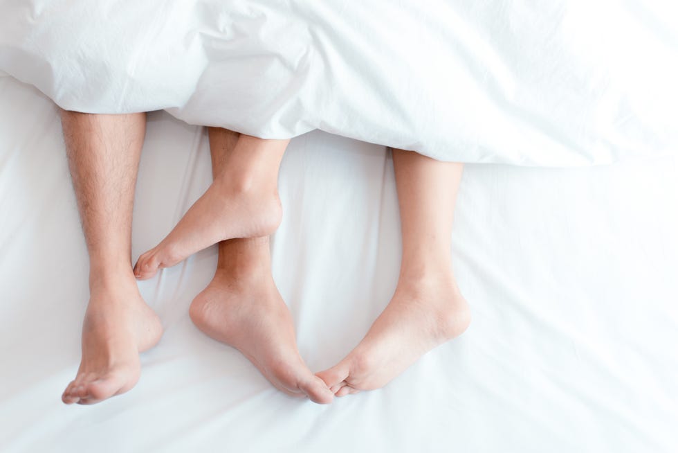 Low Section Of Couple Relaxing On Bed