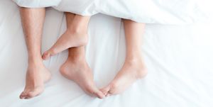 Low Section Of Couple Relaxing On Bed
