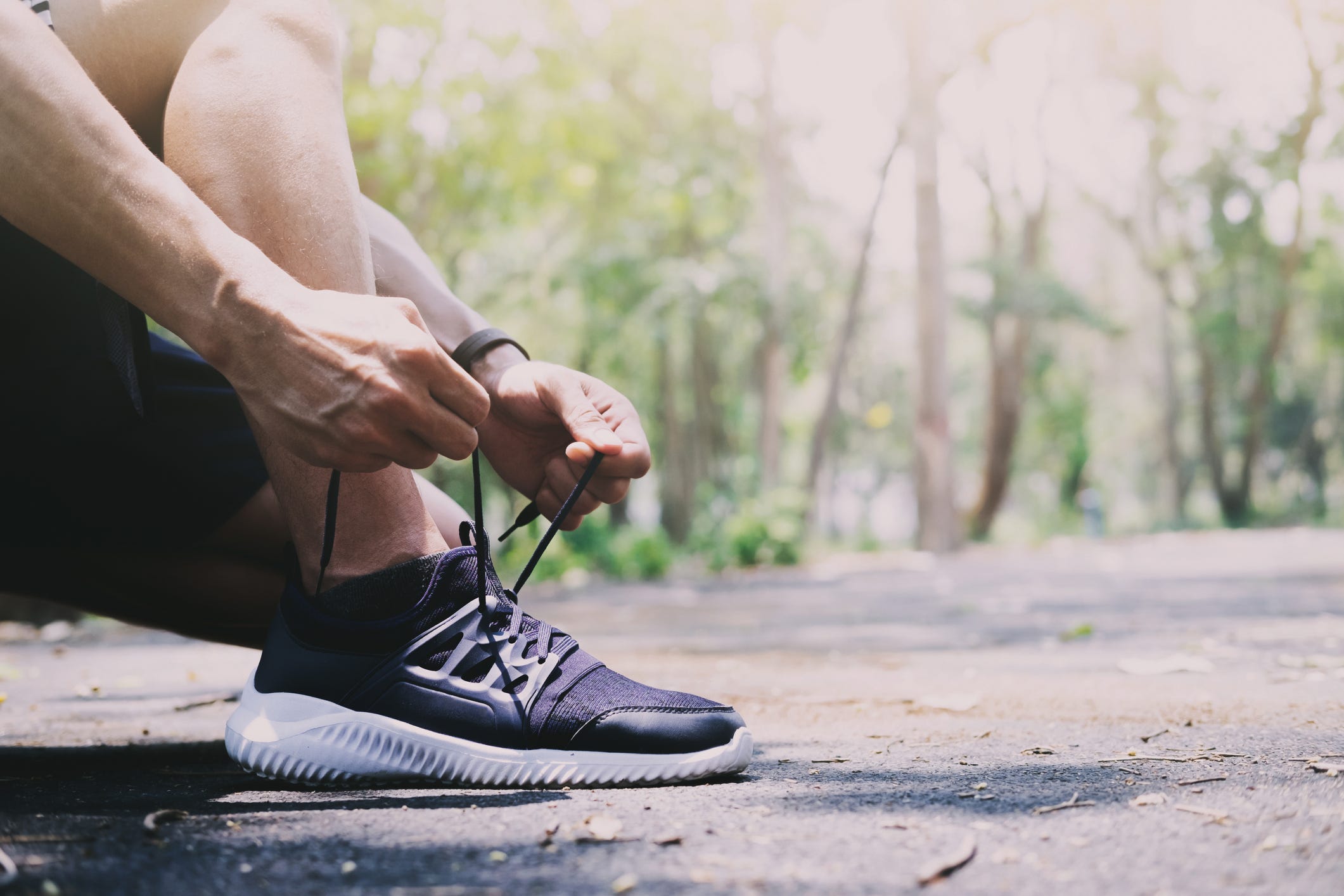 low section of man tying shoelace on road